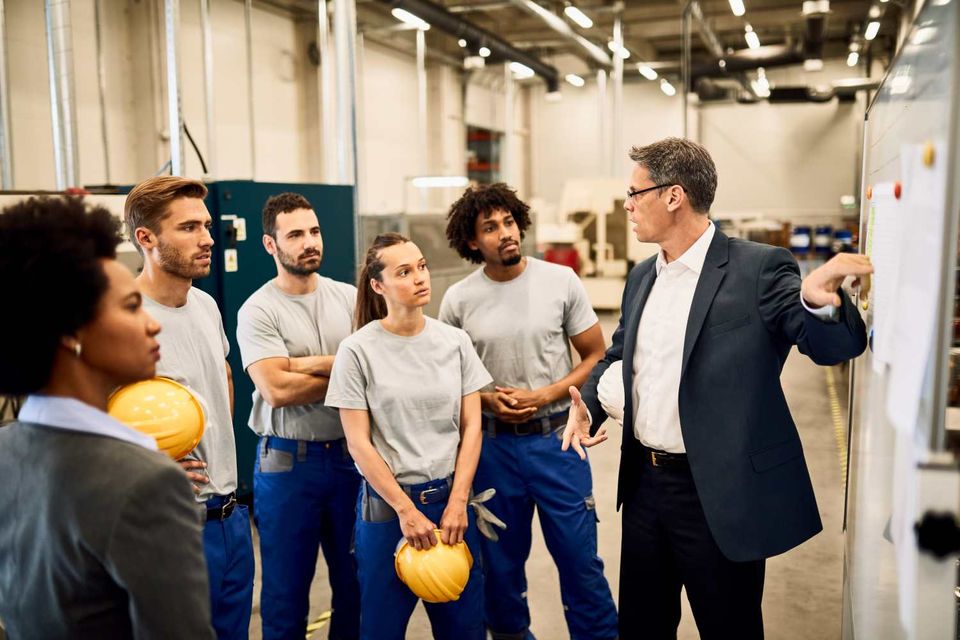 Mid adult businessman giving presentation group industrial workers factory