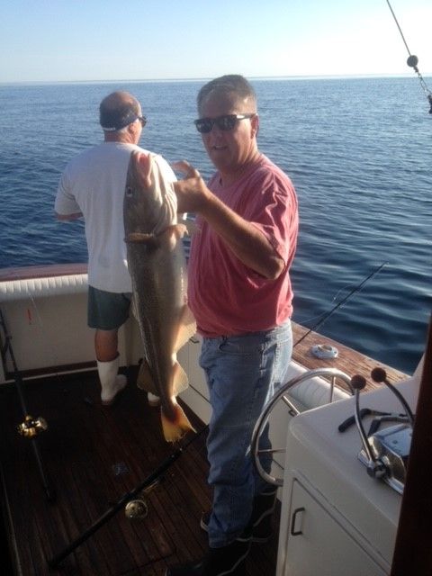 Two men on back of boat one holding up a haddock