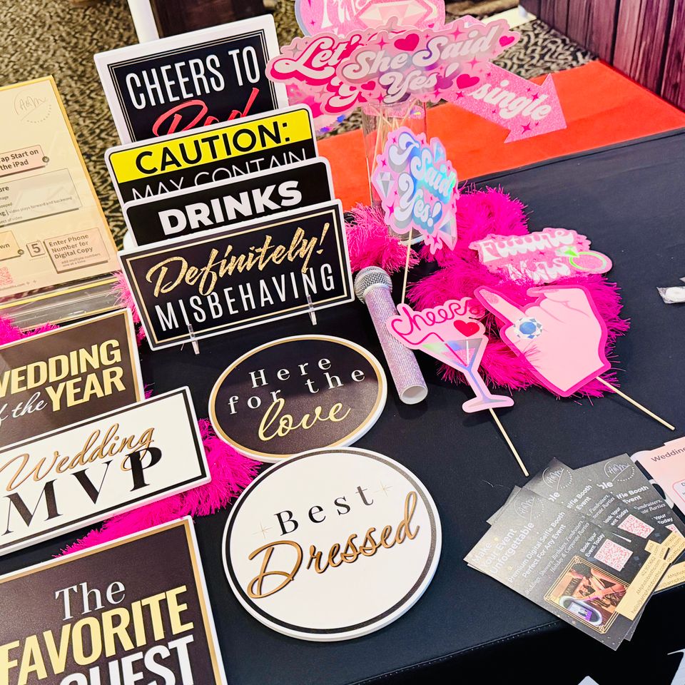 Close-up of wedding-themed photo booth props with fun phrases and decorative elements.