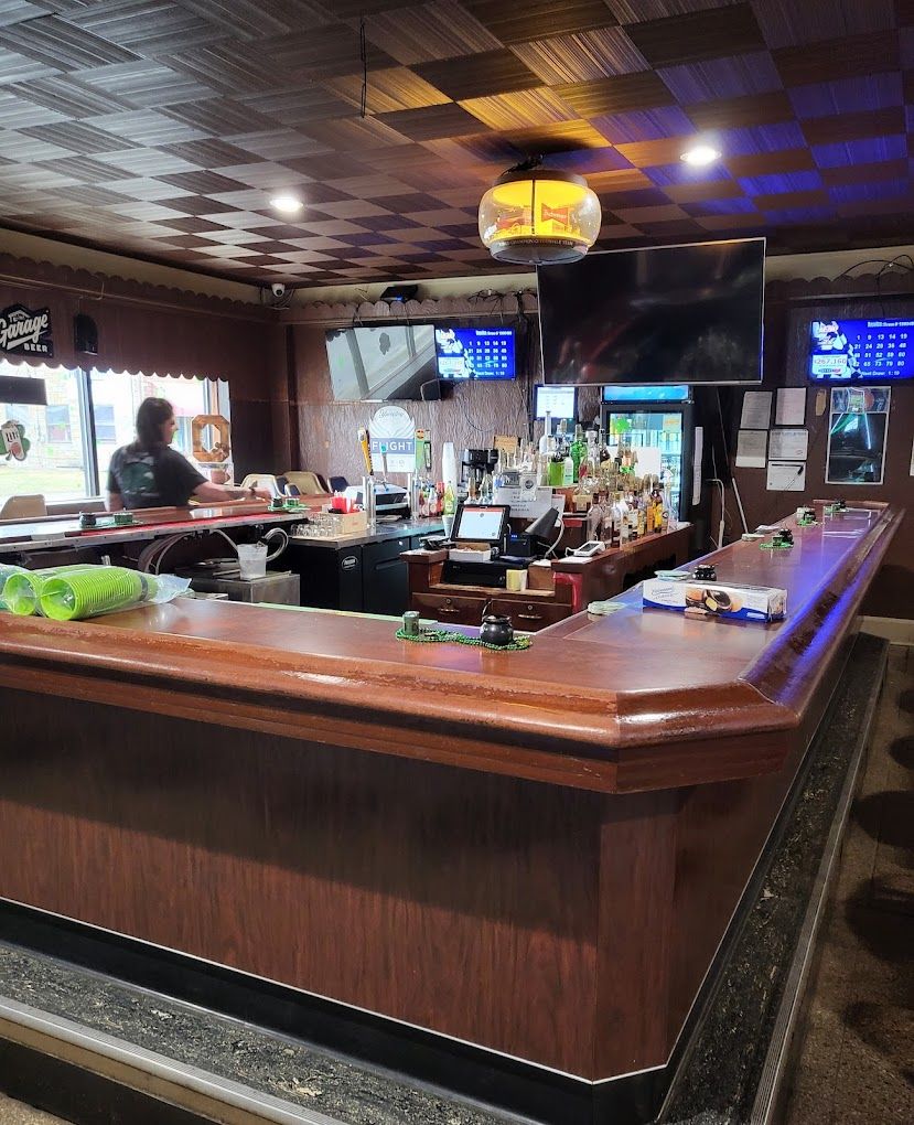 Interior of Village Tavern bar with wooden counter, drinks, and TVs