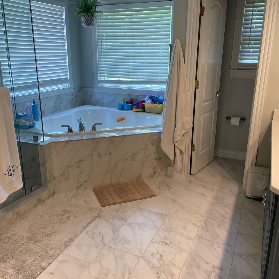 Spotless marble bathroom with corner tub and glass shower after a house cleaning service in Virginia Beach VA