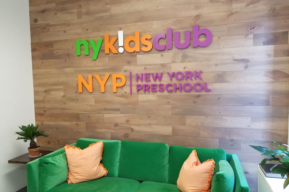 Dimensional letters reading NY Kids Club and New York Preschool mounted on a wood plank reception wall