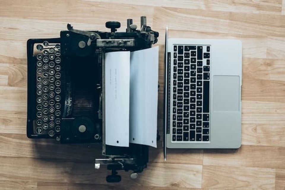 Old school typewriter butted up against an Apple Macbook 
