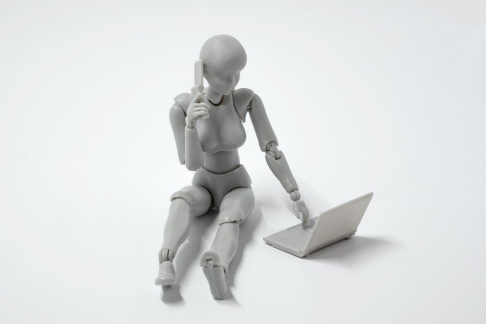 A solo AI robot (wooden toy painted white) on a laptop with a phone to its ear