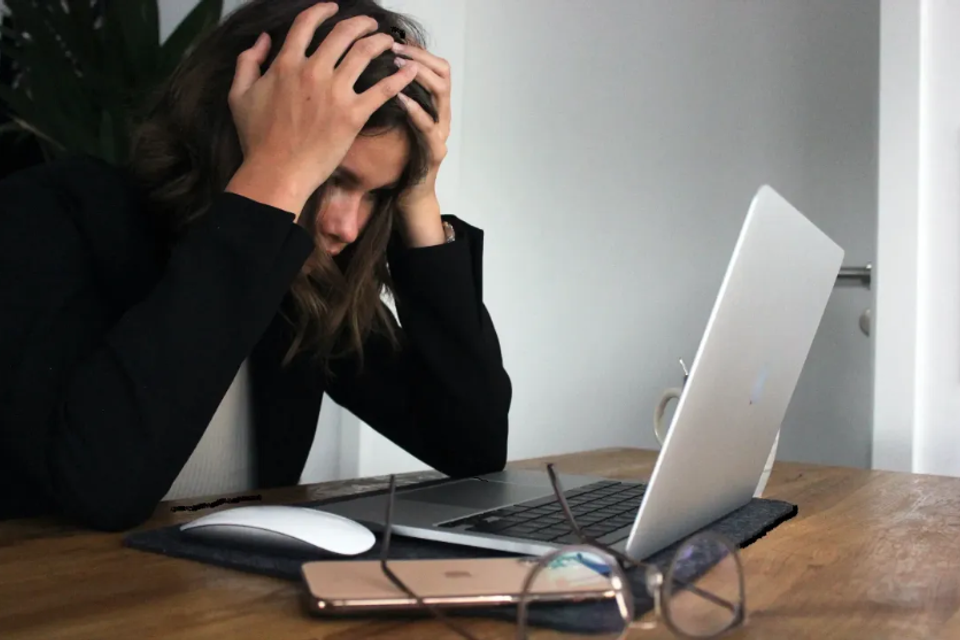 Frustrated real estate agent sitting in front of laptop, struggling with DIY website design for their business.