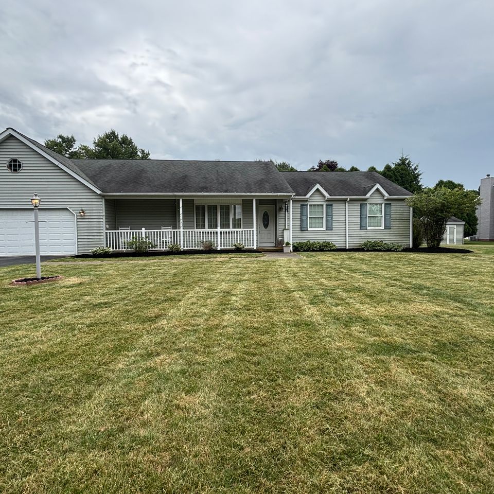 Wide view of a residential front yard featuring a striped lawn, fresh mulch beds, and a well-maintained home exterior.