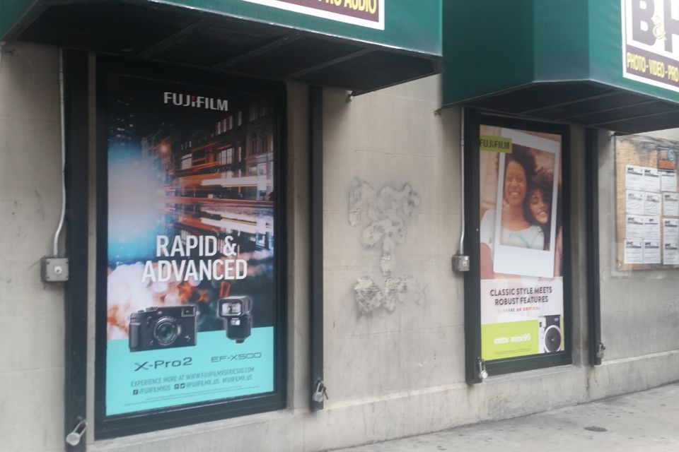 Printed product graphics filling two recessed display windows beside a retail storefront awning