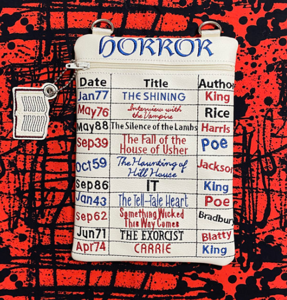 Custom embroidered zipper pouch designed like a library checkout card listing famous horror novels and authors.