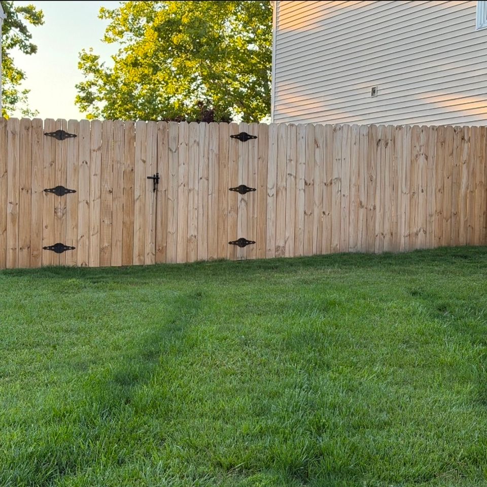 Wood dog-ear privacy fence with gate and decorative hinges in backyard in Virginia Beach VA