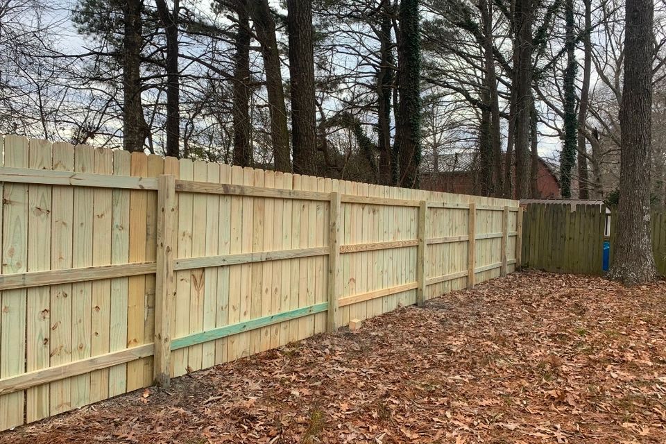 Wood dog-ear privacy fence with horizontal rails installed along wooded backyard in Virginia Beach VA