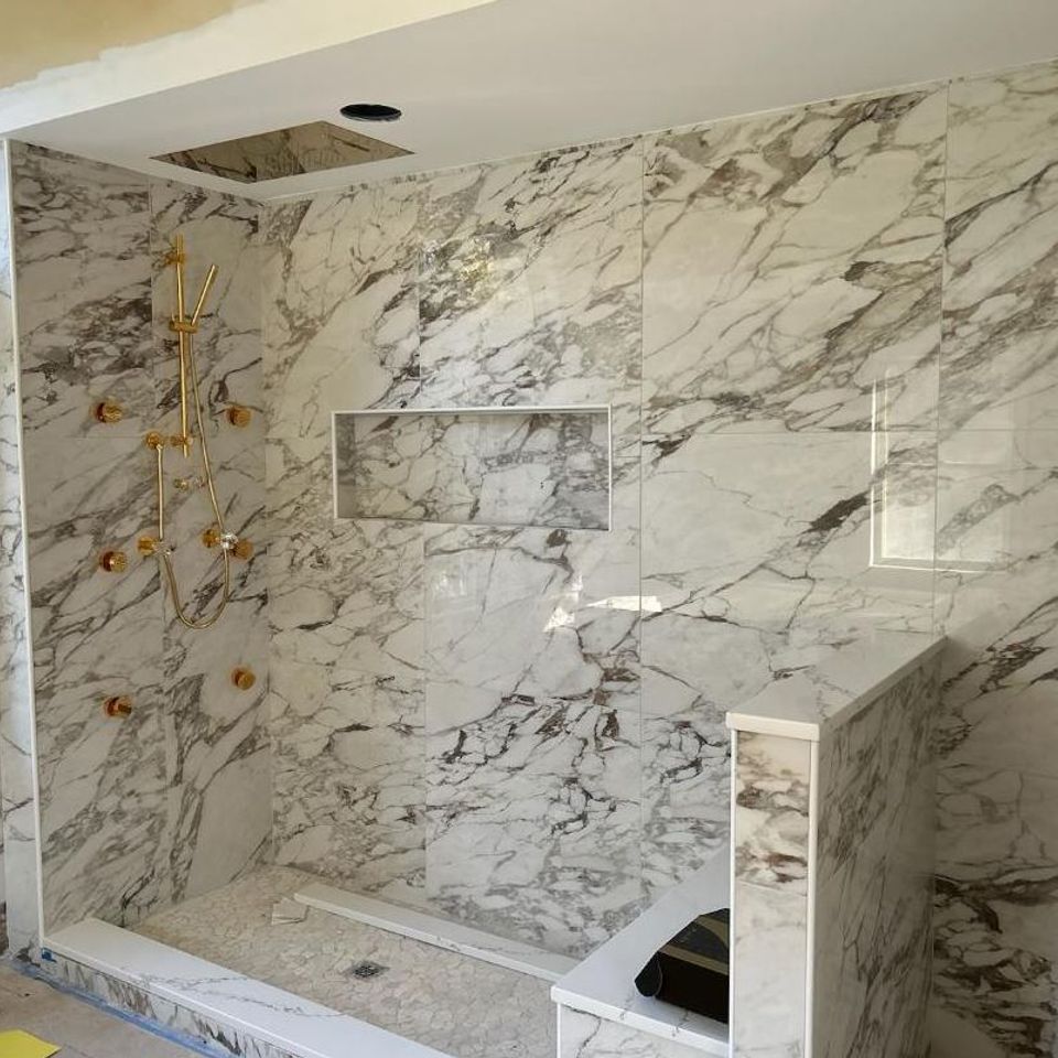 Marble tile shower remodel with gold fixtures by general contractor in Suffolk County NY