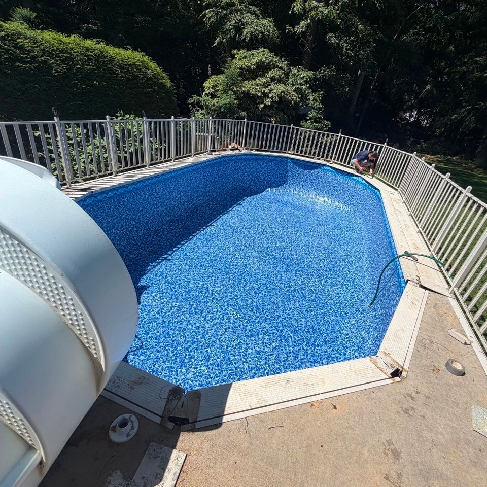 Oval above ground pool with new liner and surrounding safety fence after installation