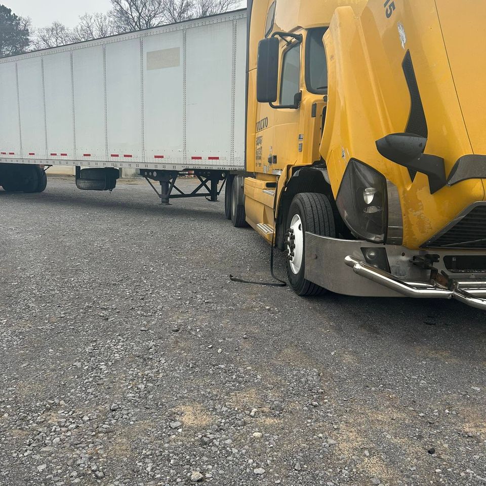 Yellow Volvo semi-truck with hood open during roadside diesel repair in Arab Alabama