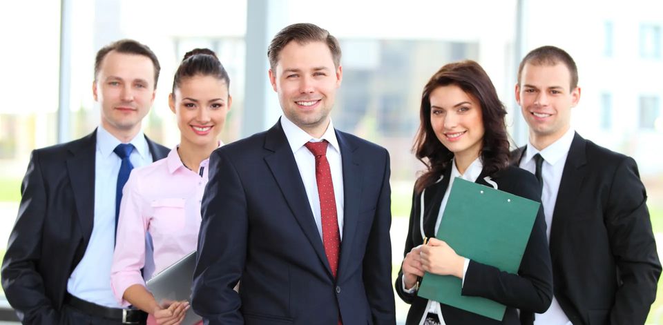 Photo of 5 people in business attire looking professional and smiling