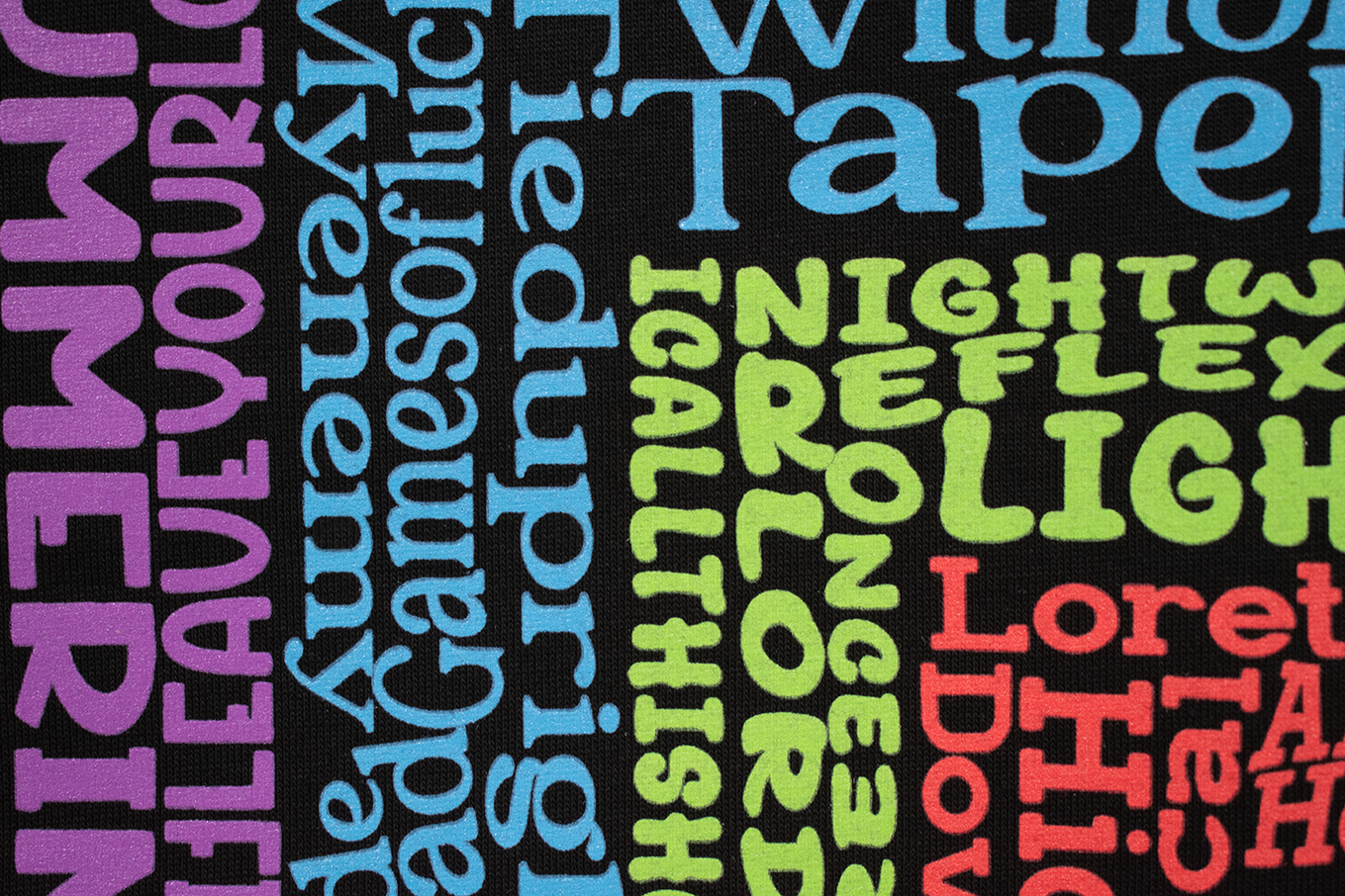 Close detail of the colorful song-title lettering on black fabric