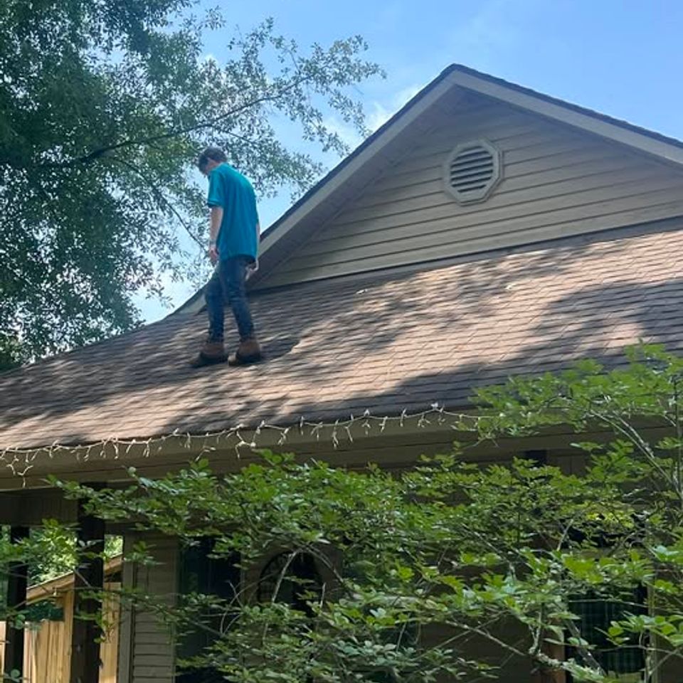 Teal project manager inspecting a roof for damage in Denham Springs, LA
