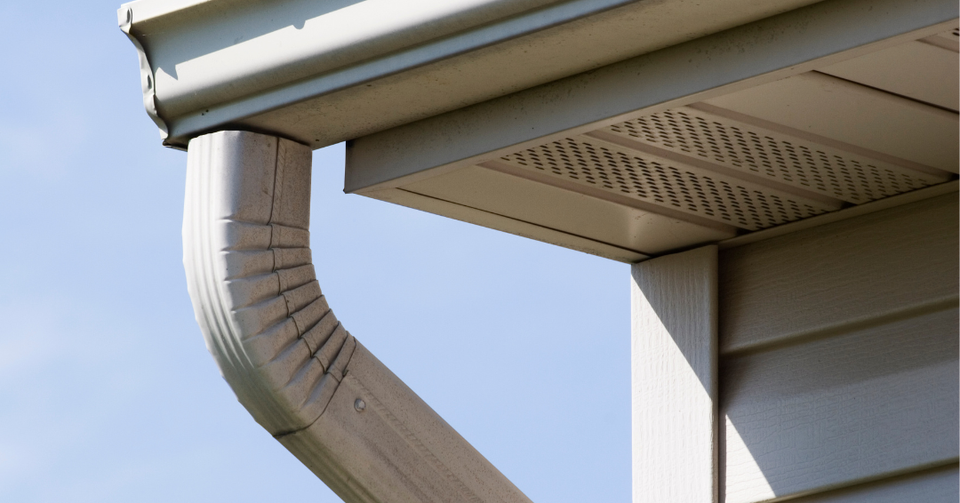 Close-up of a white seamless gutter and downspout system installed on a residential home by E & D Roofing, Inc.