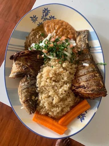 Fried whole fish platter with couscous, carrots and fresh onion tomato relish at a Cameroonian restaurant in LA
