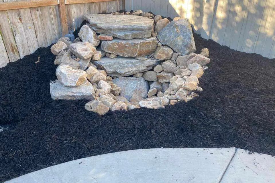 Decorative rock feature surrounded by freshly installed black mulch.