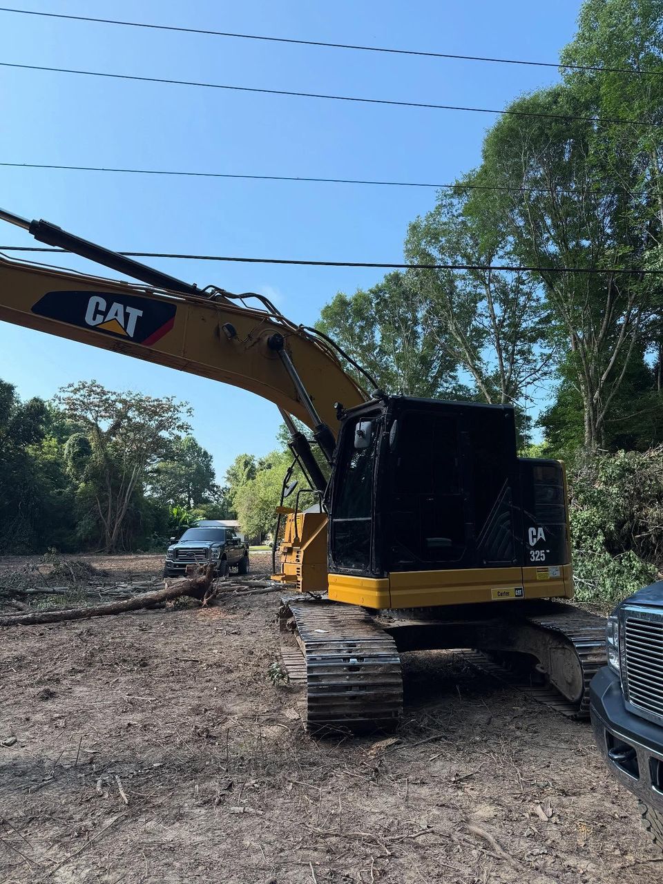 Cat 325 excavator with dark tinted cab glass on a land clearing site after heavy equipment tint in Moyock NC