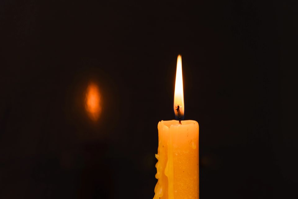 One light candle burning brightly in the dark background