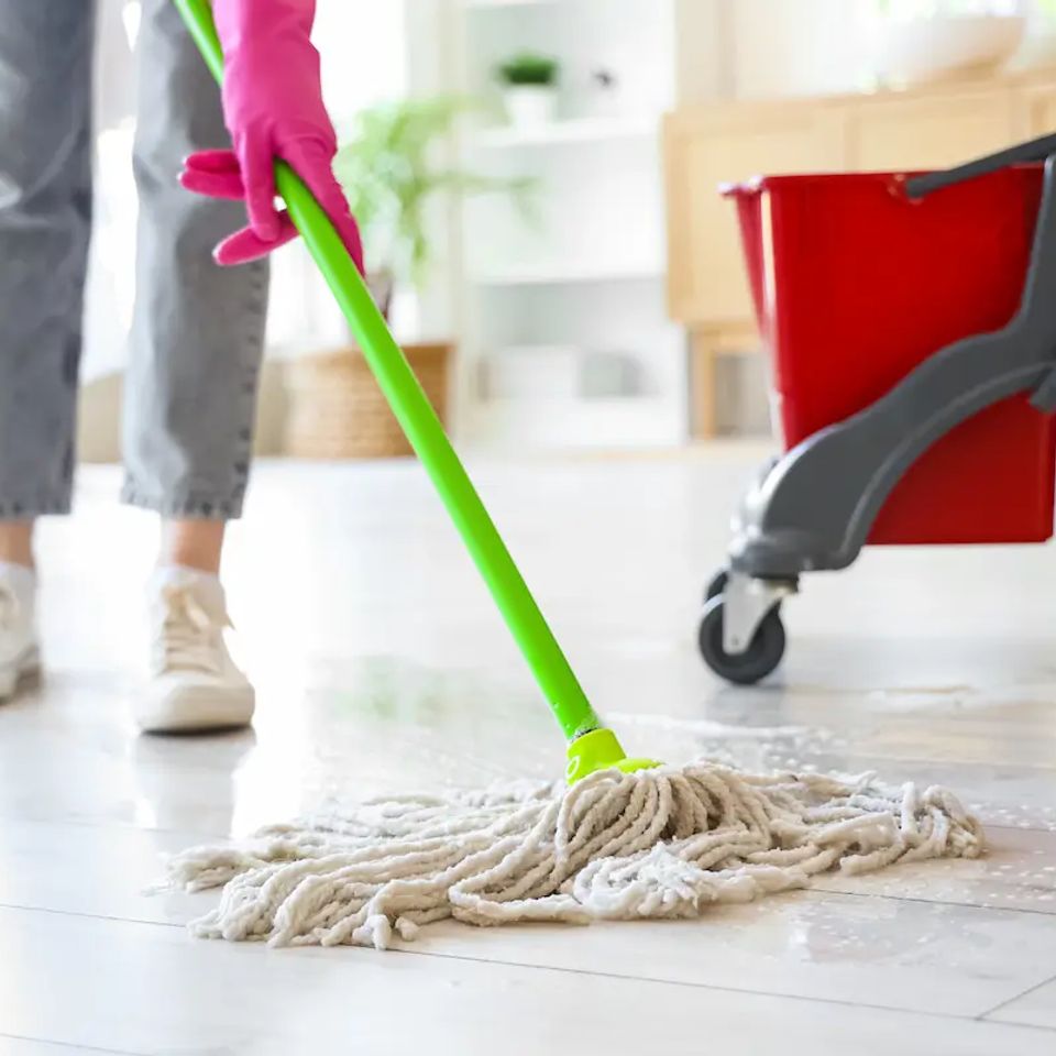 Gloved cleaner mopping tile floor with red bucket during house cleaning service in Virginia Beach VA