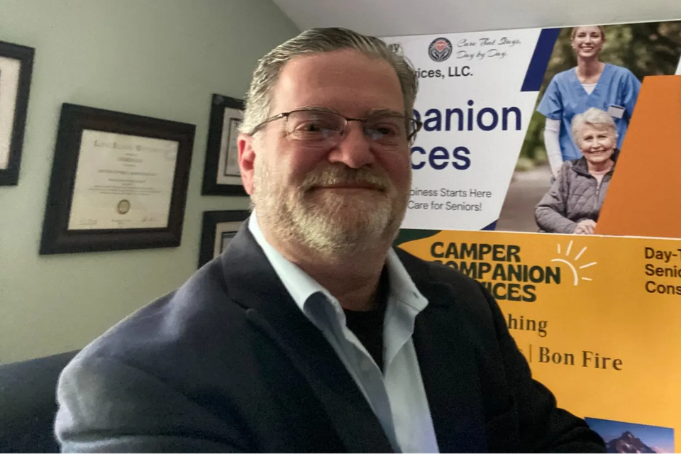 Charles Day founder of Day to Day Senior Care beside companion services signage on Long Island NY