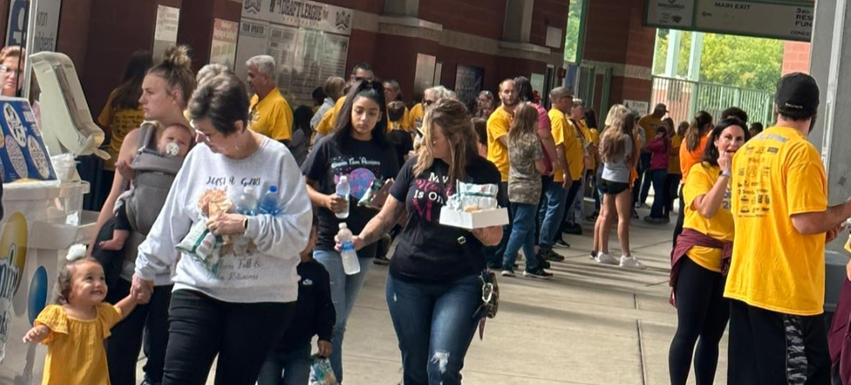 Buddy Walk attendees gathering around the event concourse with families, volunteers, and refreshments.