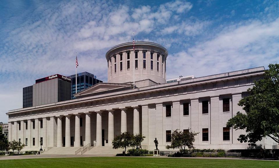 Ohio Statehouse building in Columbus, Ohio, with its large dome and American flags.