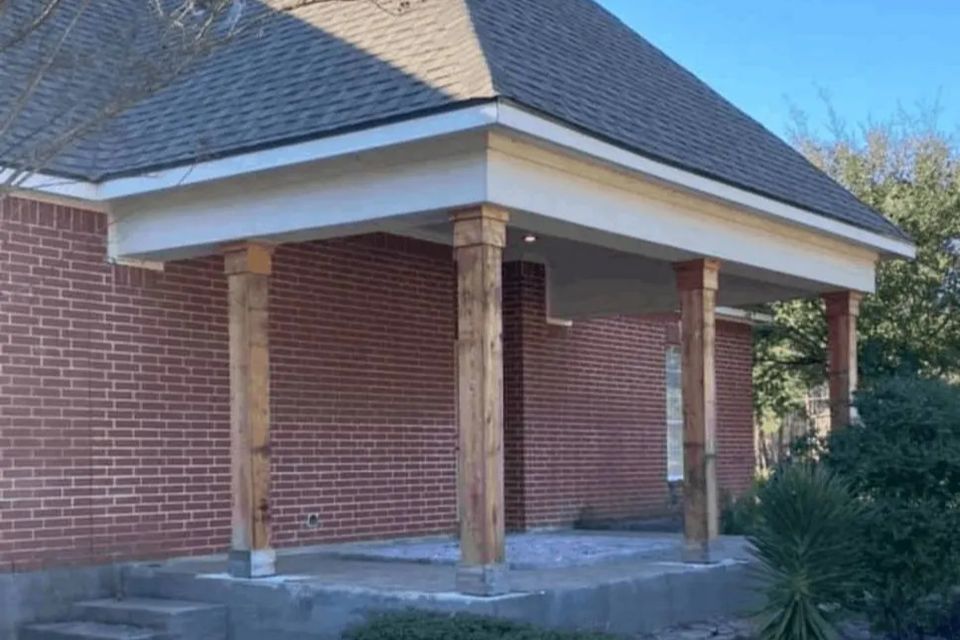 Before photo of an enclosed porch project with wood columns and concrete slab