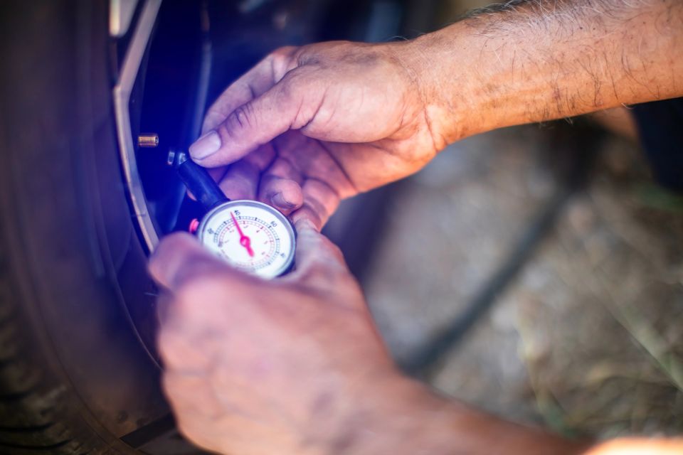 Selective focus to dirty hands of mechanic checking tire pressure using gauge