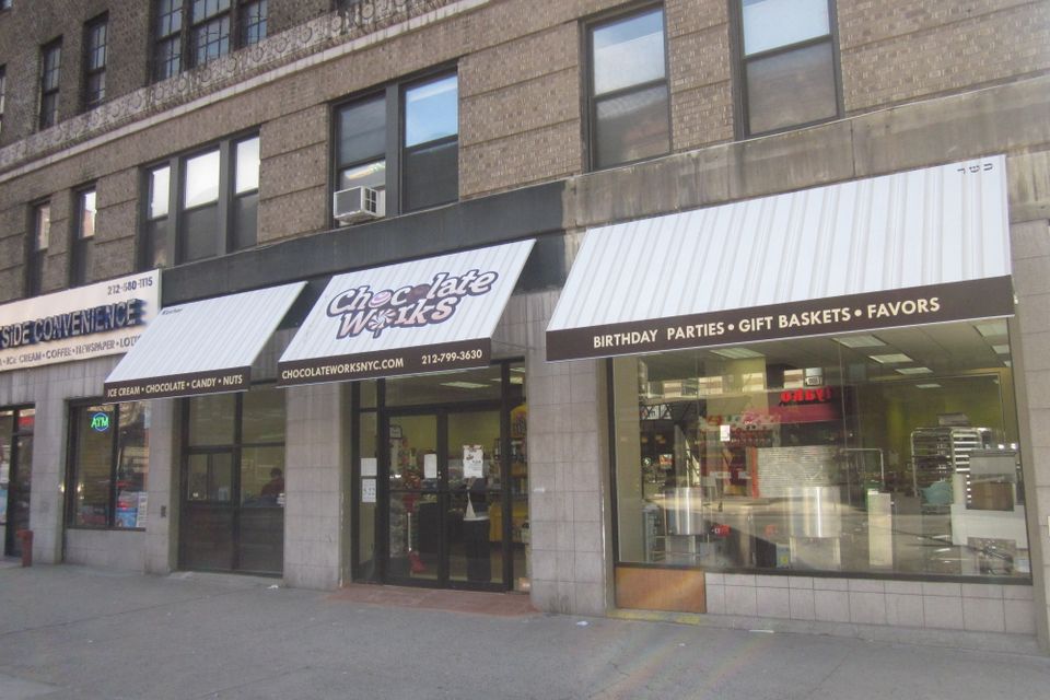 Row of cream storefront awnings with printed lettering across three adjoining retail bays on a New York City building