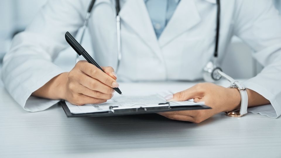 A doctor writing down notes on a clipboard
