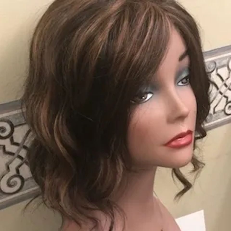 Medium-length brunette wig with soft waves and side-swept bangs displayed on a mannequin at Shears Wigs & Hairpieces Salon.