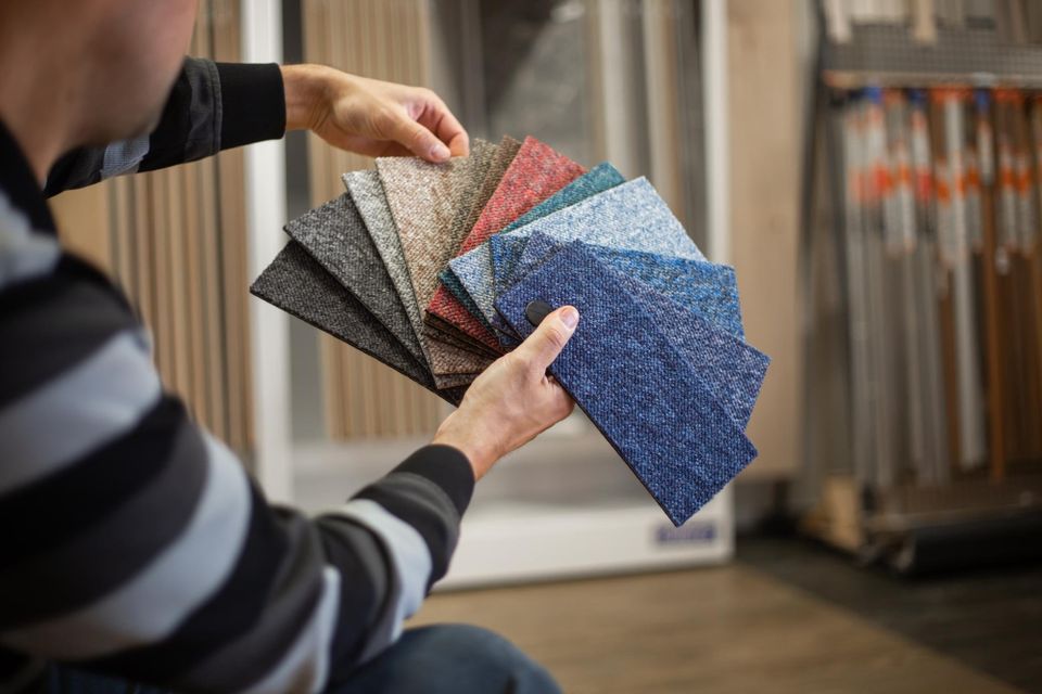 Homeowner comparing various premium carpet swatches and textures provided by Concord Carpet And Hardwood to find the perfect residential flooring match.