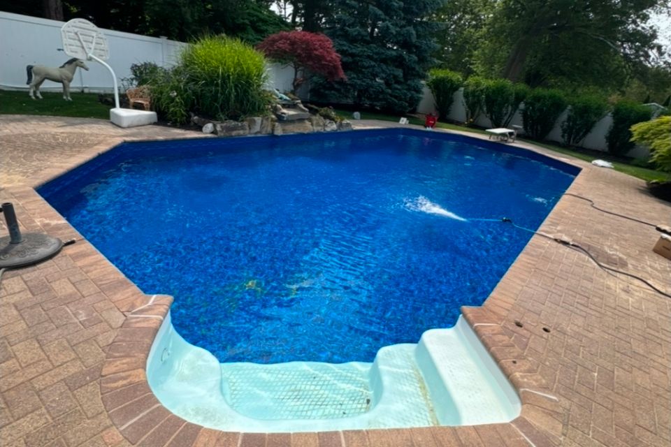Freshly filled inground pool with new blue liner and paver patio at a Long Island NY home