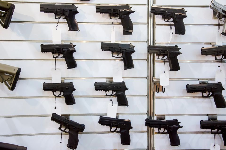 Wall display of black handguns with price tags in a gun shop