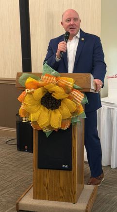 Speaker holding a microphone and speaking at a podium during the Mahoning Valley September meeting.