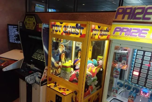 Toy Chest claw machine filled with colorful stuffed prizes inside Cocca’s Pizza arcade area.