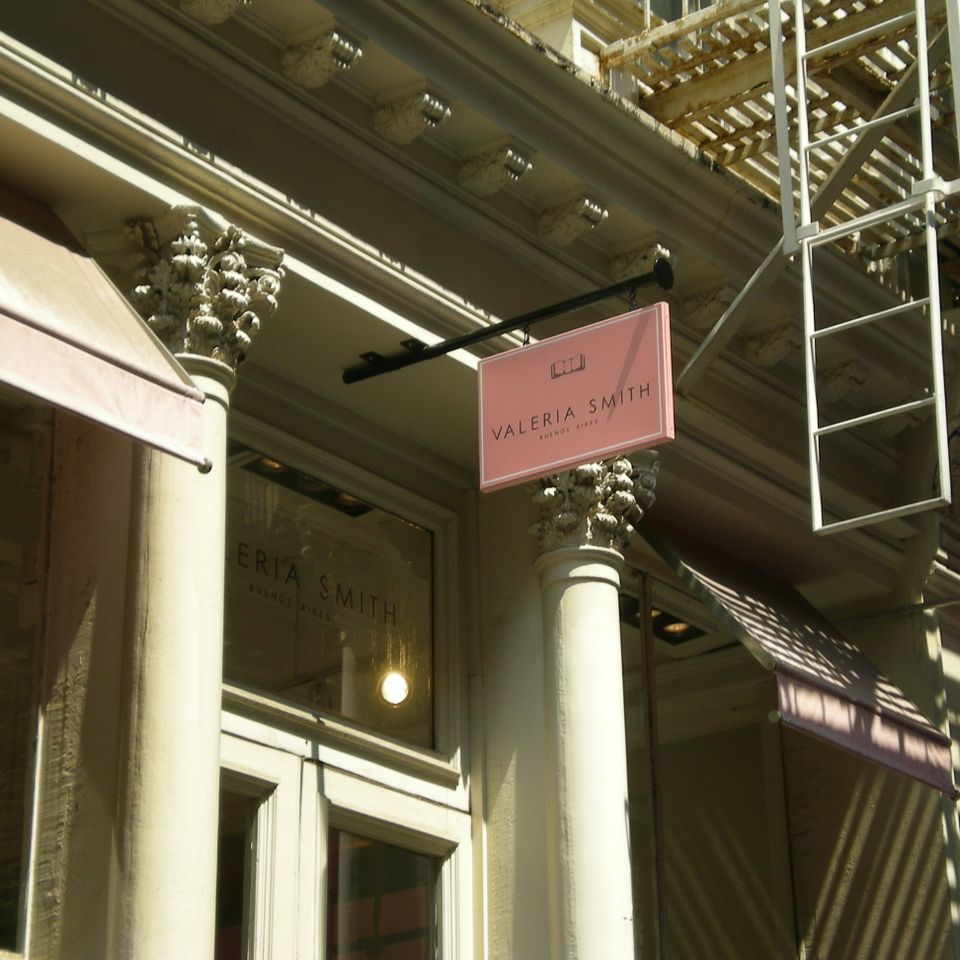 Pink pan-formed blade sign projecting from a cast-iron SoHo facade above a boutique entrance