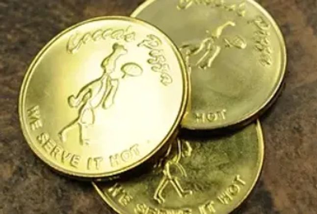 Cocca’s Pizza arcade tokens displayed on a tabletop.