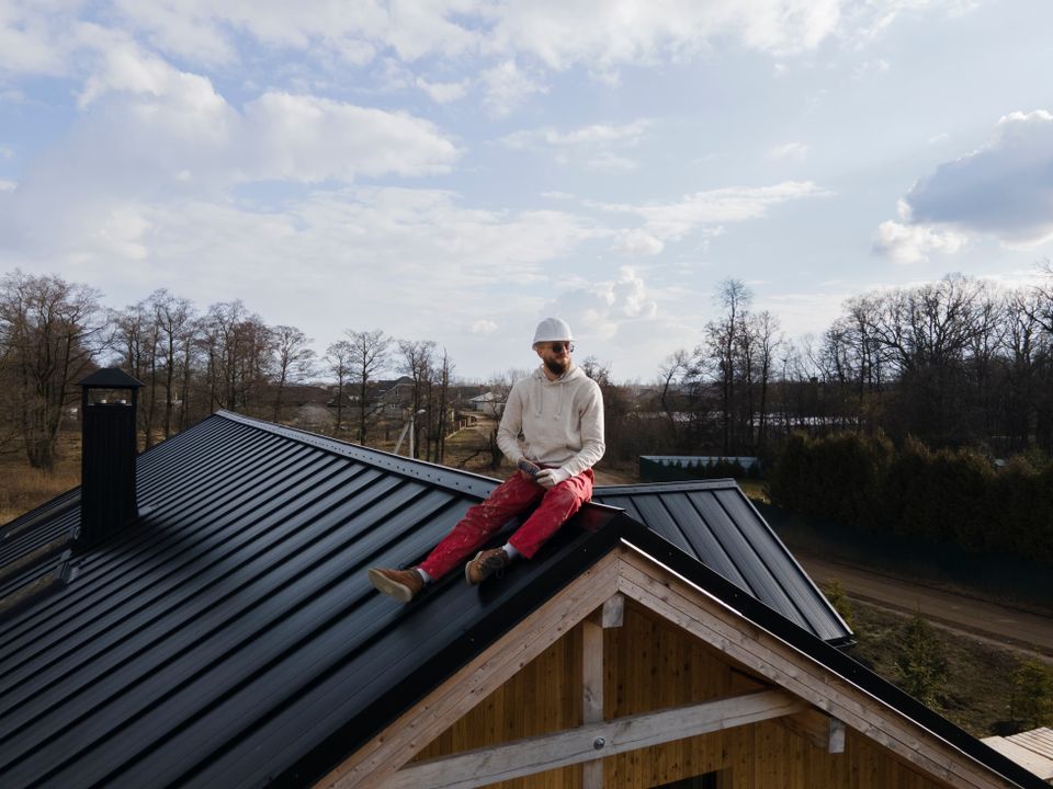 Full shot man with helmet sitting roof (1)