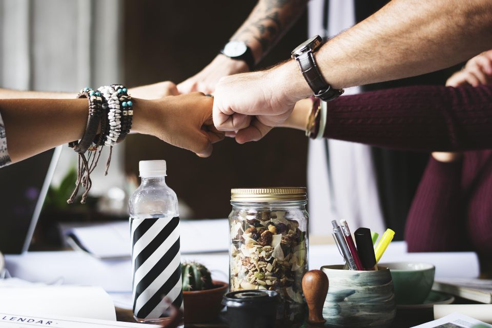 five people fist bumping over a table