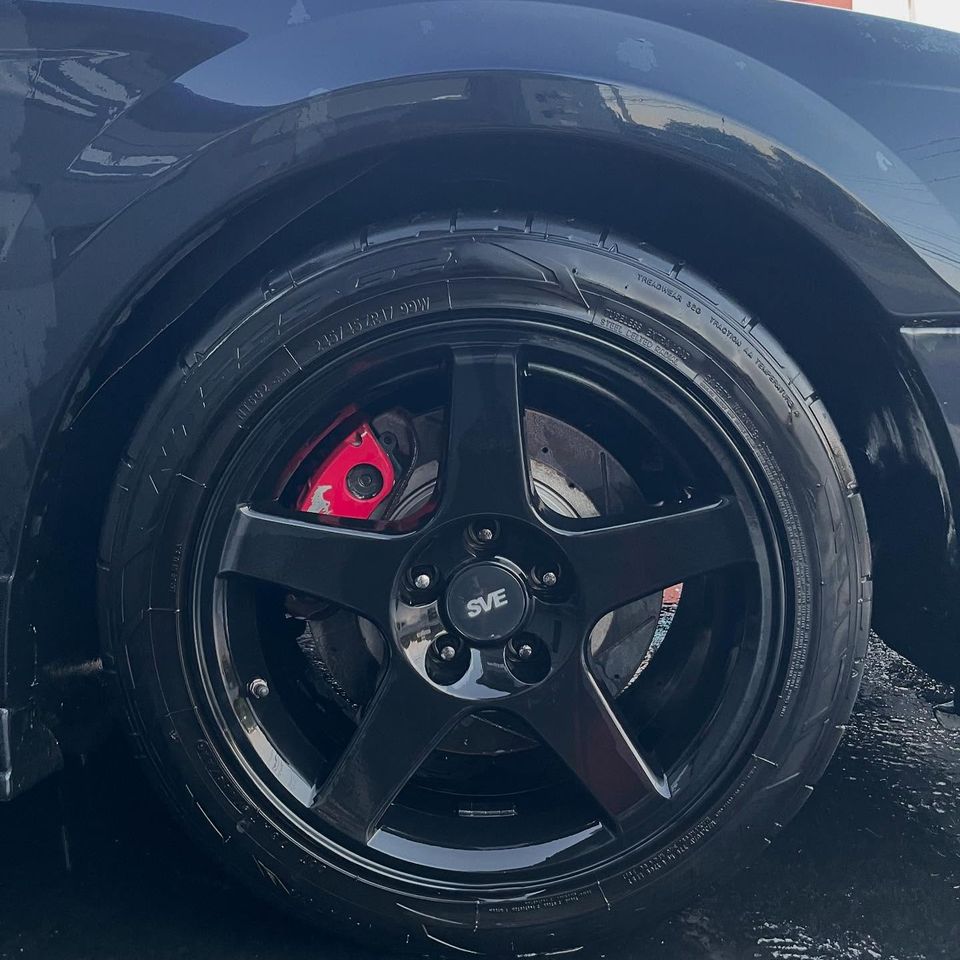 Glossy black SVE wheel with red brake caliper and dressed tire after an exterior wash