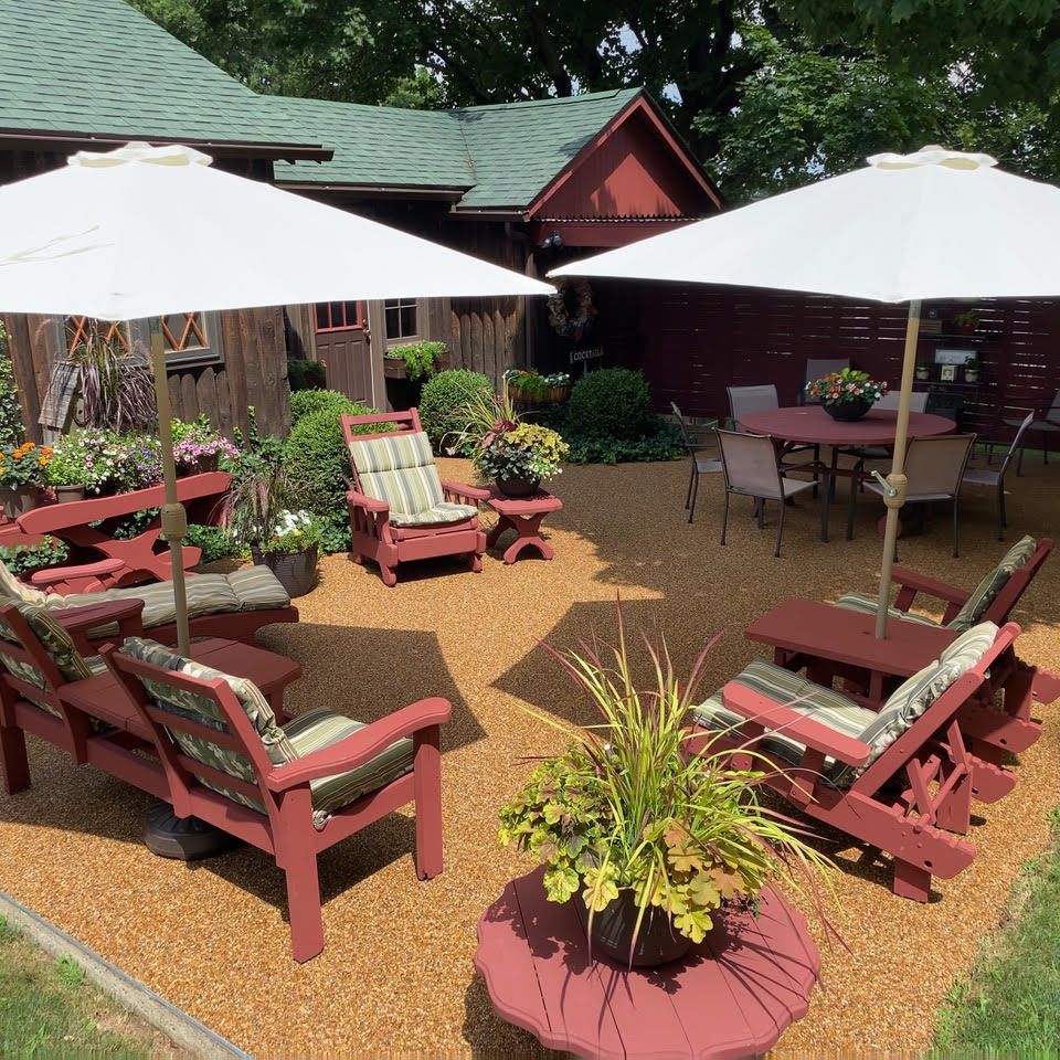 Backyard patio with decorative stone flooring, outdoor seating, umbrellas, and landscaped gardens.