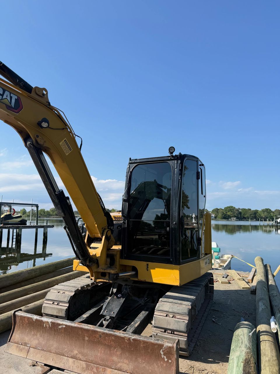 Cat excavator with tinted cab windows working on a waterfront dock in Moyock NC