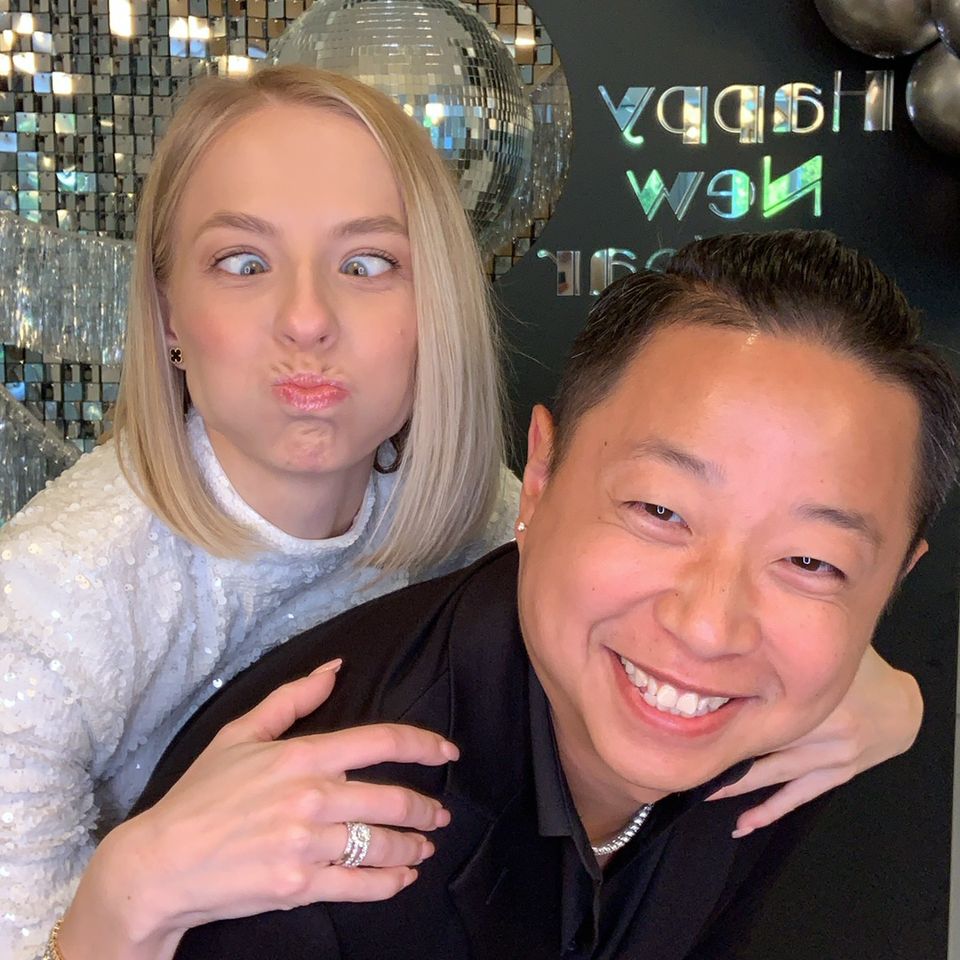Couple taking a fun selfie at an event with a photo booth backdrop.