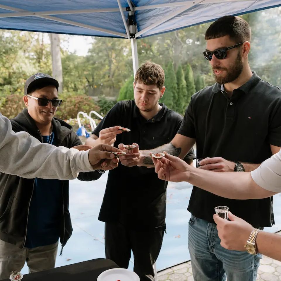 Group of guys enjoying a raw bar catering event, done by Shore2Shore Shucking of Long Island