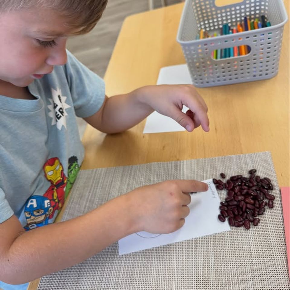 Preschool boy placing beans along a traced line during a Montessori fine motor activity in Palmdale CA