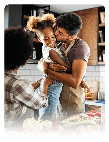 Father hugging child as mother looks on.